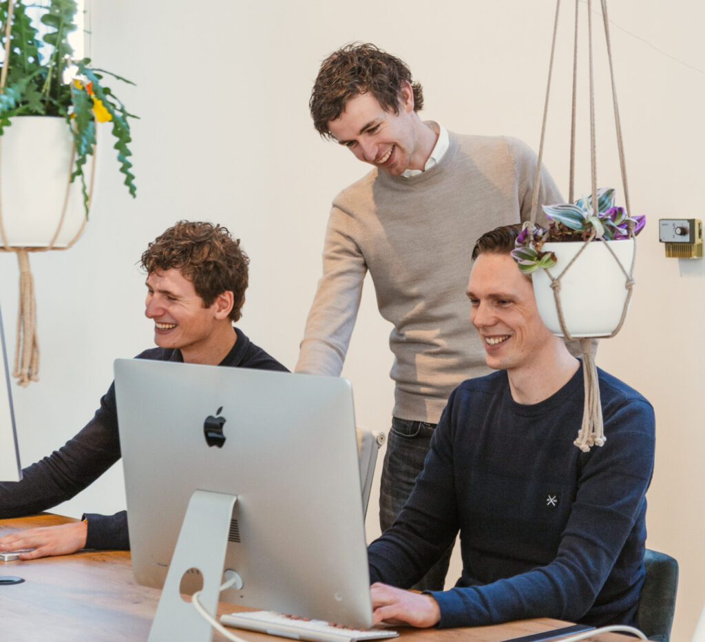 Functioneel beheer drie lachende simplex medewerkers achter een computerscherm