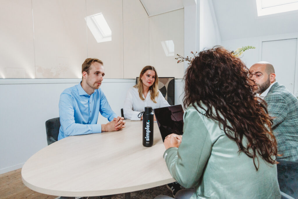 vier simplex medewerkers die in gesprek zitten aan tafel