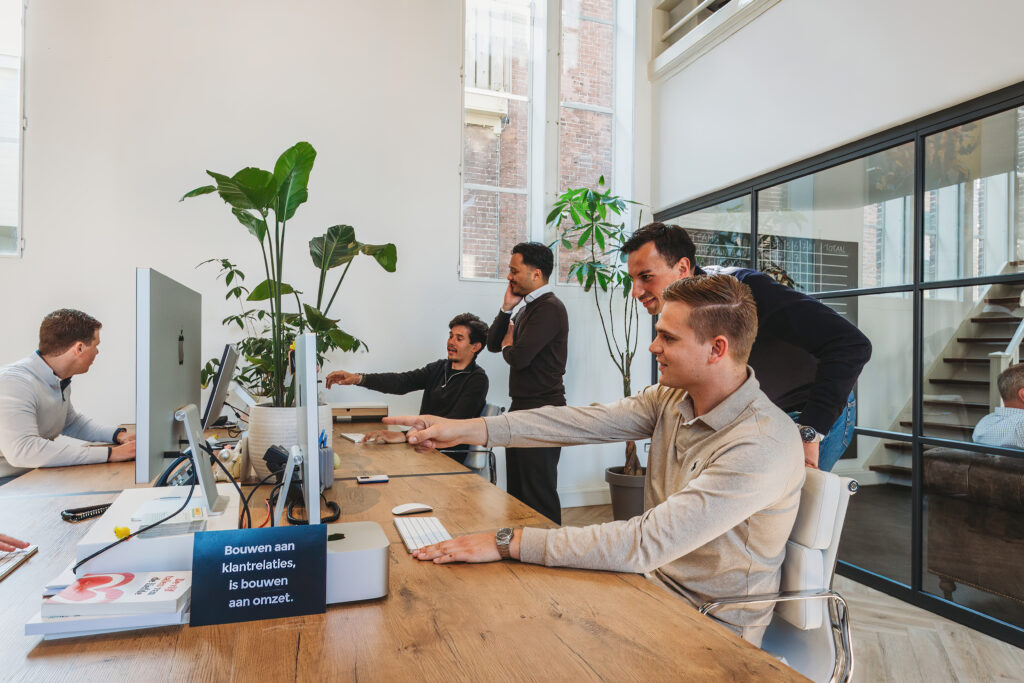 Simplex Go. vier medewerkers in overleg aan tafel met laptop